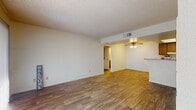 This single-floor residence offers a practical and comfortable layout with consistent wood-look flooring flowing throughout every room, creating a cohesive and easy-to-maintain living environment. The open living area is spacious and welcoming, featuring a textured ceiling, a ceiling fan with light fixture, and a large sliding glass door dressed with vertical blinds that floods the space with natural light. A raised bar counter connects the living area to the galley-style kitchen, which is well-appointed with warm wood cabinetry, ample upper and lower storage, light-toned countertops, a double stainless steel sink, and white appliances including a coil-burner range and refrigerator. The residence includes multiple bedrooms, each finished with the same wood-look flooring, crisp white walls, and windows that bring in natural light. Two bathrooms serve the home — one featuring a walk-in shower with a sliding glass door and a vanity with a speckled countertop, and the other offering a full tub-shower combination alongside a matching vanity. Textured ceilings are consistent throughout, adding subtle dimension to each room. The overall design is clean, functional, and move-in ready.