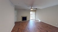 This two-floor, 2-bedroom, 2-bathroom residence offers a well-designed layout with a variety of attractive features throughout. The main living area is anchored by rich hardwood-style flooring, a ceiling fan with integrated lighting, and a tile-surround fireplace that serves as a focal point. A sliding glass door floods the space with natural light and provides outdoor access. The open flow continues into a second living or dining area, also featuring hardwood-style floors and a ceiling fan, with a pass-through window connecting to the kitchen. The galley-style kitchen is equipped with light wood cabinetry, granite-style countertops, a double sink, and black appliances including a range, microwave, and refrigerator. Both bedrooms feature plush carpet, vaulted ceilings, ceiling fans, and windows that bring in natural light. Each of the two bathrooms includes a granite-style vanity countertop with a large mirror, and a tub-shower combination with white tile surround. The overall ambiance of the residence is neutral and inviting, with consistent finishes across both floors that create a cohesive and functional living environment.