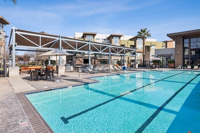 Apartamentos Aspire Tracy California Vida de lujo Una gran piscina frente a un edificio con palmeras. - Aspire Apartments