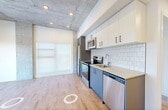 This well-designed two-bedroom, two-bathroom unit at 12322 102 Ave NW offers a contemporary living experience across a single floor. The open-concept living and kitchen area serves as the heart of the home, showcasing a striking exposed concrete ceiling with recessed pot lighting, warm light wood flooring, and a large window that frames sweeping city views while flooding the space with natural light. The kitchen is outfitted with stainless steel appliances, two-tone cabinetry in white and slate grey, a subway tile backsplash, and ample counter space. Both bedrooms are bright and functional, each featuring large windows with urban views and light wood flooring. The primary bedroom includes a sliding-door closet with built-in shelving, while the second bedroom similarly benefits from generous natural light and outdoor views. The two bathrooms are finished in a clean, modern style, featuring dark-hardware fixtures, grey vanity cabinetry with light countertops, and a full tub-shower surround. Connecting the rooms are well-proportioned hallways that maintain a cohesive, airy feel throughout. The overall design emphasizes clean lines, a neutral palette, and thoughtful finishes.