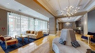 Located in the heart of Houston's vibrant Montrose district, this expansive single-floor facility spans a generously proportioned footprint, offering a seamlessly curated blend of luxury and function. The reception and living area greets guests with warm golden travertine tile floors, a coffered ceiling adorned with a striking contemporary chandelier, and a richly detailed reception counter. Sophisticated wall paneling and curated artwork establish an elevated ambiance throughout.

The hallway is lined with large-format polished tile floors, geometric-patterned wallcoverings, and floor-to-ceiling mirror panels that amplify the sense of space and light, with sheer drapes softening the corridor's sleek aesthetic. A dedicated meeting or dining room impresses with deep navy walls, an ornate crystal-and-brass chandelier grouping, and a polished wood table surrounded by plush velvet seating.

The spacious fitness center is fully outfitted with professional-grade cardio and strength equipment, floor-to-ceiling mirrors, decorative pendant lighting, and ceiling fans. Treatment rooms offer an intimate, moody atmosphere with textured walls and carefully considered lighting. The lounge area provides a relaxed retreat with tufted seating, bold artwork, and floor-to-ceiling windows overlooking an outdoor pool area, filling the room with natural light.