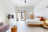 Located at 300 Cherokee Blvd in Chattanooga, Tennessee, this single-floor studio offers a thoughtfully designed open-concept layout that seamlessly integrates living, sleeping, and dining areas into one cohesive space. Soaring ceilings with exposed ceiling fans and track lighting amplify the sense of openness throughout, while smooth polished concrete floors provide a clean, contemporary foundation that ties the entire space together.

The living area features a plush modular sectional sofa paired with a round wood side table and a flat-screen TV atop a white dresser, offering a comfortable and functional lounge space. A compact dining area with a round black table and modern chairs adds a defined social zone without interrupting the open flow of the room. A kitchenette tucked along one wall provides essential appliances and cabinetry for daily use.

The sleeping area is bathed in natural light from large floor-to-ceiling sliding glass doors that open directly to a private outdoor patio, creating an effortless indoor-outdoor connection. A rattan folding screen adds a warm, organic design element to the bedroom zone.

The bathroom is finished with clean subway tile wainscoting, a floating wood vanity with black metal accents, and a backlit mirror, delivering a refined and modern aesthetic. Throughout the space, a neutral warm palette and natural materials create a calm, inviting ambiance.