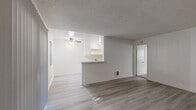 Located in Huntington Beach, CA, this single-floor 2-bedroom, 2-bathroom home offers a clean, functional layout with a bright and neutral aesthetic throughout. The open living area features light vinyl plank flooring, crisp white walls, and a sliding glass door with vertical blinds that floods the space with natural light and provides access to an outdoor patio. A ceiling fan adds comfort to the living and dining area. The kitchen runs parallel to the living space and is equipped with white cabinetry, light stone-look countertops, a stainless steel double sink, a white range, and a peninsula breakfast bar that connects to the main living area — ideal for casual dining and entertaining. The bedrooms are carpeted for warmth and comfort; the spacious primary bedroom includes a generous closet and a window with a view of outdoor greenery. The second bedroom features vinyl plank flooring and a textured accent wall with board-and-batten paneling detail. Both bathrooms are clean and functional, with one featuring a full tub-and-shower combination with chrome fixtures and a natural light window above the tub. Textured ceilings are consistent throughout the home, adding a classic residential character to the overall space.