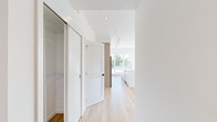 This well-designed 2-bedroom, 2-bathroom residence offers a clean, modern aesthetic throughout its efficiently laid-out single floor. Light hardwood flooring flows consistently through every room, complementing the crisp white walls and creating a bright, cohesive interior.

The open-plan kitchen and living area serves as the heart of the home, featuring stainless steel appliances, white upper cabinetry paired with warm wood-toned lower cabinets, quartz countertops, and a white tile backsplash. Large windows flood the living space with natural light and provide sweeping views of the surrounding cityscape and beyond.

Both bedrooms are well-proportioned, with the primary bedroom offering dedicated closet storage with built-in shelving. Each room benefits from generous window coverage, ensuring ample daylight and scenic outdoor views. The second bedroom also features direct access to a large private terrace finished with large-format pavers and a glass railing, offering expansive panoramic views of the city and mountains.

The two bathrooms are finished consistently with vertically laid tile surrounds in the tub-shower combinations, wood-look flooring, and clean white vanities. Hallways are thoughtfully organized, with built-in closet storage providing practical solutions throughout the residence.