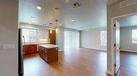 This single-floor residence features a contemporary design with warm wood-look flooring carried consistently throughout every room. The open-concept kitchen and living area form the heart of the unit, where a well-appointed kitchen stands out with a two-tone cabinet scheme pairing warm walnut-toned lower cabinets with crisp white upper cabinetry. A generous central island with a white quartz countertop provides both prep space and casual seating. Stainless steel appliances, including a refrigerator, range, microwave, and dishwasher, complete the kitchen. Pendant lighting above the island and recessed ceiling lights illuminate the space, while a window above the sink brings in natural light. The kitchen flows seamlessly into a spacious living area featuring windows on multiple walls and a sliding glass door, filling the room with natural light. A ceiling fan adds practical comfort. The full bathroom includes a single-sink vanity with walnut cabinetry, a large mirror, and a tub-shower combination. A second bathroom functions as a combined bathroom and laundry room, housing a washer and dryer alongside a single-sink vanity. The bedroom is a quiet, neutral room with a window and direct access to a walk-in closet fitted with multiple shelving tiers and hanging rods.