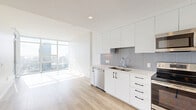 Located at 1150 E Street in San Diego's vibrant East Village, this modern one-bedroom, one-bathroom residence offers a thoughtfully designed layout across a single floor. The open-concept living, dining, and kitchen area is the heart of the home, bathed in natural light streaming through expansive floor-to-ceiling windows that frame sweeping city skyline views. Light-toned hardwood flooring flows seamlessly throughout, enhancing the bright and airy atmosphere. The kitchen is outfitted with sleek white cabinetry extending to the ceiling, a grey subway tile backsplash, light quartz countertops, and a full suite of stainless steel appliances including a refrigerator, range, microwave, and dishwasher. A private balcony, accessible via glass sliding doors, extends the living space outdoors with open urban views. The bedroom features mirrored sliding closet doors and direct access to the balcony through floor-to-ceiling glazing, filling the room with natural light. The bathroom is finished with marble-style tile on both the floors and shower surround, complemented by a soaking tub and a clean white vanity. A dedicated laundry area and additional closet storage add everyday practicality to this polished, contemporary residence.