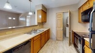 Located at 40 Deer Lakes Dr in Buffalo, New York, this single-floor unit offers a well-organized layout designed for comfortable everyday living. The open living area is finished with plush wall-to-wall carpeting, warm neutral-toned walls, and generous windows dressed with horizontal blinds that allow natural light to fill the space. A front entry door with glass accent panels adds a welcoming touch to the main living room.

The kitchen is thoughtfully appointed with warm oak cabinetry, a double stainless steel sink, and ample counter space. A pendant light overhead adds a functional accent, and a dedicated laundry area is conveniently accessible just off the kitchen. The dishwasher and additional cabinetry provide practical storage and utility throughout.

The bedrooms continue the carpeted aesthetic, each featuring windows with natural light and ceiling fans for year-round comfort. The rooms offer a clean, neutral palette well-suited for a variety of furnishing styles.

Two full bathrooms serve the unit, both finished with warm wood vanity cabinetry, dark countertops, and light tile flooring. One bathroom includes a tub/shower combination, while the other features a standalone vanity with a large mirror. Together, the bathrooms provide functional and well-finished spaces that complement the overall design of the home.