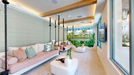 Located at 1464 Laurel Sound Lane in Sanford, Florida, this thoughtfully designed single-floor community space offers a welcoming and resort-inspired atmosphere. The open-plan layout is anchored by wide-plank light hardwood flooring that flows throughout the main gathering area, complemented by recessed lighting and clean white walls that create a bright, airy ambiance.

A standout architectural feature is the dedicated lounge alcove, where rope-suspended swing beds hang from exposed wood-beam ceilings with warm accent lighting. Shiplap walls in a soft sage green lend a coastal character to this zone, while light brick-style tile flooring adds textural contrast. A vivid hand-painted tropical mural depicting lush palm trees and a serene waterscape serves as a dramatic focal point, reinforcing the Florida-inspired design narrative.

The main social area accommodates multiple seating arrangements, including woven rattan chairs and neutral upholstered sofas, making it ideal for both casual gatherings and relaxed lounging. Large floor-to-ceiling glass panels and sliding doors flood the space with natural light and offer direct views of an outdoor pool area, seamlessly blending the interior with the surrounding environment.

Overall, the space presents a cohesive tropical-coastal aesthetic, balancing playful design elements with comfortable, functional communal living.