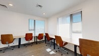 Located at 2005 Brook Rd in Richmond, Virginia, this contemporary office suite offers a well-appointed, single-floor layout comprising a dedicated office workspace and a conference/dining room. The office area is bright and airy, benefiting from an abundance of natural light streaming through large windows fitted with roll-down shades. Multiple workstations with clean-lined desks and ergonomic wood-and-chrome swivel chairs are arranged to maximize productivity, all set atop durable, neutral-toned carpet. Recessed lighting and a modern HVAC vent complete the clean, white ceiling.

The adjacent conference room exudes a polished, professional ambiance. A long, light wood conference table with built-in cable management ports is flanked by rich cognac leather chairs, offering seating for multiple attendees. A striking textured stone accent wall provides an eye-catching focal point, complemented by floating wood shelves and integrated cabinetry below. Recessed lighting ensures a well-lit environment, while a glass-panel black-framed door with sidelights elegantly connects the two spaces, maintaining visual openness. Touches of greenery add warmth to the overall minimalist aesthetic, making this suite a refined and functional professional environment.