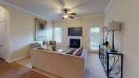 This single-story space is designed with a warm, neutral color palette throughout, creating a cohesive and inviting atmosphere across all rooms. The living room serves as the central gathering area, highlighted by a fireplace with a clean white mantel, crown molding, a ceiling fan, and multiple windows with blinds that allow natural light to fill the space. A door provides direct outdoor access, enhancing the open feel of the room.

The dining area features hardwood-style flooring, crown molding, and an elegant chandelier that anchors the intimate setting. The galley-style kitchen offers warm wood cabinetry, light countertops, a stainless steel refrigerator, and hardwood-style flooring, with a utility area visible through a connecting doorway.

Both bedrooms are carpeted and equipped with ceiling fans. The primary bedroom includes a door to the outside and coastal-themed wall art, while the secondary bedroom features a walk-in closet with built-in shelving. The primary bathroom includes a double-sink vanity with warm wood cabinetry, a wide mirror, and tile flooring, providing ample functionality and storage throughout the space.