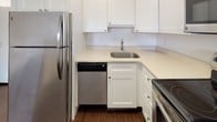 Located at 2 Shipway Place in Boston's Charlestown neighborhood, this single-floor unit offers a clean, modern design with a thoughtfully open layout. Rich, dark hardwood-style flooring flows continuously through the main living area, creating a warm and cohesive aesthetic against crisp white walls and trim.

The living area is generously proportioned, offering an open and airy feel that connects seamlessly to the kitchen via a pass-through peninsula. The kitchen is well-equipped, featuring white shaker-style cabinetry, light stone countertops, a stainless steel refrigerator, dishwasher, and range. A single-basin stainless steel sink with a gooseneck faucet anchors the counter space, while ample upper and lower cabinetry provides excellent storage.

The bedroom is a bright, comfortable retreat, benefiting from two large windows that invite natural light and offer views of surrounding greenery. The same dark hardwood-style flooring continues here, maintaining the unit's consistent design language.

The bathroom is finished with light ceramic floor tile and white wall tile surrounding a full soaking tub with a shower. Grab bars and a clean vanity complete the space, reflecting both function and simplicity.

A closet off the main hallway adds practical storage, rounding out this well-designed unit in one of Boston's most sought-after neighborhoods.