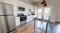 This contemporary apartment in Louisville, Kentucky showcases a thoughtfully designed open floor plan. The heart of the home is a pristine kitchen, boasting white cabinetry, stainless steel appliances, and a subway tile backsplash. A central island with seating provides additional workspace and a casual dining area. The living room is anchored by a stylish electric fireplace, offering both warmth and ambiance. Large windows with plantation shutters flood the space with natural light, while plush carpeting in the bedrooms ensures comfort underfoot. The bathroom features a modern vanity, large mirror, and a glass-enclosed shower. Throughout the apartment, a neutral color palette creates a serene atmosphere, complemented by the warmth of wood-look flooring in common areas. High ceilings and recessed lighting add to the spacious feel, making this apartment an ideal blend of style and functionality.