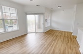 This 610-square-foot, one-bedroom, one-bathroom apartment at Ovaltine Court in Villa Park, IL offers a well-designed single-floor layout with modern finishes throughout. The open-concept living room and kitchen area features light hardwood-style flooring, a ceiling fan, and large windows with horizontal blinds that invite natural light. A sliding glass door provides additional outdoor views and access. The kitchen is equipped with stainless steel appliances including a refrigerator, microwave, and range, complemented by gray shaker-style cabinetry, white quartz countertops, a peninsula with an undermount sink, black fixtures, and a subway tile backsplash. The 140-square-foot bedroom is carpeted for comfort and includes a ceiling fan and a window with outdoor views. The bathroom features marble-look tile surround in the tub/shower combo, black fixtures, wood-look flooring, and a white vanity. A dedicated in-unit laundry room with full-size side-by-side washer and dryer adds everyday convenience. The unit also includes a hallway and closet, maximizing functional storage within the compact floor plan. Clean white walls and consistent finishes give the space a cohesive, contemporary feel.