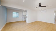 Located at 1230 E First St in Long Beach, CA, this thoughtfully updated 2-bedroom, 1-bathroom single-floor home offers a clean, modern aesthetic from entry to end. Light wood-tone flooring runs seamlessly throughout, tying each room together with a warm, cohesive feel. The open living room is bright and airy, featuring a ceiling fan, recessed lighting, a wall-mounted mini-split system for climate control, and large windows dressed with white blinds that invite natural light. A soft blue accent wall adds a touch of color to the living space. The galley-style kitchen is well-appointed with white shaker cabinetry, matte black hardware, quartz countertops, a stainless steel sink, and a full suite of stainless steel appliances including a gas range, microwave, and refrigerator. The primary bedroom offers a comfortable footprint, a ceiling fan, natural light, and a mirrored sliding closet. The second bedroom is equally well-lit with its own ceiling fan. The full bathroom features a white vanity with quartz countertop, matte black fixtures, a soaking tub with shower, and a small privacy window. Recessed lighting throughout and clean white walls give the entire home a fresh, move-in ready appearance.