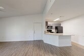 Located in Spring, TX, this 1-bedroom, 1-bathroom unit offers a thoughtfully designed single-story layout with a clean, modern aesthetic. The open-concept living, dining, and kitchen area is anchored by vaulted ceilings and light-toned wood-look flooring that extends throughout the main living spaces, creating a bright and airy feel. French doors lead to a private patio, flooding the living area with natural light and providing easy outdoor access.

The kitchen features gray cabinetry, granite-look countertops, a peninsula with bar seating, and black appliances including a refrigerator, range, and microwave — all set against a neutral tile backsplash. A dedicated dining space connects seamlessly to the living area, making the layout ideal for everyday living and entertaining.

The bedroom is carpeted for comfort and includes a ceiling fan with light fixture and a walk-in closet. A hallway connects the bedroom to the full bathroom, with additional closet storage accessible along the way. The unit also includes a dedicated laundry room equipped with a full-size washer and dryer. The exterior features classic brick accents, adding to the unit's lasting curb appeal.