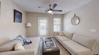 Located at 1523 Roswell Rd in Marietta, GA, this single-floor, 2-bedroom, 2-bathroom residence offers a thoughtfully designed layout that maximizes comfort and functionality. The open-concept kitchen features white cabinetry, light countertops, stainless steel appliances including a refrigerator, range, and dishwasher, and track lighting overhead. It flows seamlessly into the combined dining and living area, where wood-look flooring extends throughout the main living spaces. The dining area comfortably accommodates a full-sized table and is complemented by neutral walls and a textured ceiling. The living room benefits from natural light streaming through multiple windows and a glass exterior door, with a ceiling fan adding to the airy feel. Both bedrooms are carpeted and equipped with ceiling fans; the primary bedroom features a large window with outdoor views and access to a spacious walk-in closet with wire shelving systems. The second bedroom also offers closet storage. Each bathroom includes a tiled shower-tub combination with a classic white-and-black tile accent border. A hallway connects all rooms, lending the floor plan a practical, easy-to-navigate flow throughout the home.