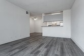 Located at 11657 Oxnard St in the North Hollywood neighborhood of Los Angeles, this single-floor unit offers a clean, functional layout designed for comfortable everyday living. The entry opens directly into a combined living and kitchen area, where a peninsula with granite-style countertops visually connects the two spaces. The kitchen is well-equipped with white cabinetry, a gas range, a full-size refrigerator, and a decorative mosaic tile backsplash that adds a touch of character. Under-cabinet lighting and a skylight contribute to a bright cooking environment. Throughout the unit, wood-style laminate flooring in a light gray tone creates a cohesive and modern aesthetic. The living area is generously sized, featuring a large window with vertical blinds that allows abundant natural light to fill the room. The bedroom offers a comfortable footprint with a mirrored closet and its own window for additional ventilation and light. The bathroom includes a full tub-and-shower combination with tile surround, complemented by wood-style flooring and a closet with built-in shelving nearby. Textured ceilings are present throughout, and a ceiling fan is installed in the bedroom area. The overall ambiance is bright, clean, and move-in ready.