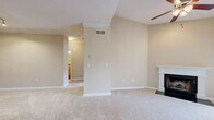 This single-floor residence offers a thoughtfully designed layout encompassing a living room, bedroom, kitchen, bathroom, hallway, closet, and dedicated laundry room. The living room is an inviting centerpiece, featuring vaulted ceilings, a ceiling fan, a classic wood-burning fireplace with a white mantel, and French doors that welcome abundant natural light and outdoor views. Soft neutral-toned carpet runs throughout the living and bedroom areas, complementing the warm beige walls and white crown molding accents. The kitchen is well-equipped with light wood cabinetry, granite-look countertops, a gray subway tile backsplash, hardwood-style flooring, track lighting, and stainless steel appliances including a refrigerator and range. The spacious bedroom accommodates comfortable furnishings, is fitted with a ceiling fan, a large window for natural light, and provides direct access to the hallway and closet. The bathroom features a full tub-shower combination with white tile surround, hardwood-style flooring, and a vanity with granite-look countertops. The in-unit laundry room houses a full-sized washer and dryer with overhead wire shelving for added storage. Overall, the space presents a clean, functional, and comfortable living environment.