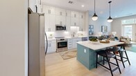 Located at 715 E College Avenue in vibrant Decatur, GA, this thoughtfully designed one-bedroom, one-bathroom residence offers a efficient and stylish single-floor layout. The open-concept kitchen and living area serves as the heart of the home, showcasing floor-to-ceiling white shaker cabinetry with matte black hardware, a clean white quartz countertop, and a striking teal kitchen island with bar seating. Stainless steel appliances, including a side-by-side refrigerator, electric range, built-in microwave, and dishwasher, complete the well-appointed kitchen. Light wood-style flooring runs throughout, adding warmth and continuity. The living area is bathed in natural light through oversized French doors with transom windows above, opening to a private balcony with outdoor views. The bedroom offers a calm, neutral palette with warm lighting and direct access to the bathroom. The bathroom features marble-style tile flooring, a white vanity with quartz countertop, and direct access to a dedicated walk-in closet with built-in shelving and hanging storage. A welcoming entrance and hallway connect all areas seamlessly, rounding out this well-organized and modern residence in the heart of Decatur.