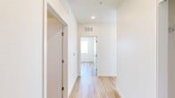 Located at 5270 Federal Blvd in Denver, CO, this modern 2-bedroom, 2-bathroom residence offers a thoughtfully designed single-level layout with clean, contemporary finishes throughout. Light wood-tone flooring flows seamlessly across the entire space, creating a bright and cohesive aesthetic.

The open-concept kitchen serves as a central highlight, featuring a large white waterfall island with an undermount sink, white upper cabinetry, light wood lower cabinets, a subway tile backsplash, and stainless steel appliances including a French door refrigerator, range, and microwave. Large windows flood the kitchen with natural light and frame sweeping views of the Denver cityscape.

The primary bedroom is generously proportioned and benefits from abundant natural light, offering panoramic city views through a large sliding glass door that opens to a private balcony. The second bedroom also features a sizable window with elevated city views. Both bathrooms are finished with light wood vanity cabinetry and white countertops, while one bathroom includes a full tub and shower with elegant marble-style tile surround.

A well-proportioned hallway connects the bedrooms and bathrooms, complete with recessed lighting and a closet. The overall ambiance is clean, modern, and airy — ideal for those seeking contemporary urban living in Denver.