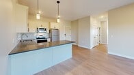 Located in Monticello, MN, this thoughtfully designed 3-bedroom, 3-bathroom residence offers a functional and modern living experience across a single floor. The open-concept kitchen and living area serves as the heart of the home, anchored by a central island with a dark quartz countertop and pendant lighting overhead. White shaker-style cabinetry, a subway tile backsplash, and stainless steel appliances — including a refrigerator, range, and microwave — complete the kitchen. Light wood-look flooring flows throughout the main living areas, enhancing the bright, airy ambiance. The living room offers access to a private balcony through sliding glass doors, filling the space with natural light and outdoor views of the surrounding landscape. The primary bedroom is generously sized with hardwood-style flooring and its own balcony access via a large window. Additional bedrooms feature plush carpeting and double-door closets for ample storage. Each of the three bathrooms is finished with wood-look tile flooring, white vanities, and clean fixtures, with at least one bathroom offering a full tub and shower combination. A hallway connects the bedrooms efficiently, and two dedicated closets provide practical storage solutions throughout.