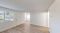 Located at 266 North El Camino Real in Oceanside, California, this single-floor, 2-bedroom, 1-bathroom home offers a clean and functional layout designed for comfortable living. The interior is finished with light-toned wood-look flooring throughout the main living areas, complemented by crisp white walls and textured ceilings that give the space a bright, airy feel. The entrance opens into a spacious living area with natural light filtering in through slatted blinds and a ceiling fan overhead, creating a welcoming and well-ventilated atmosphere. The adjoining dining room flows naturally from the living space. The galley-style kitchen features white cabinetry lining both walls, a double-basin sink, ample counter space, and a range, providing an efficient and organized cooking environment. The primary bedroom offers generous square footage with wood-look flooring and direct access to the full bathroom, which includes a vanity with white cabinetry, a mirror, and a tub-shower combination. The second bedroom is carpeted and includes a window for natural light. A standout feature of this home is its exceptional storage, with four closets including a large walk-in closet fitted with built-in shelving and hanging rods. A private patio completes this well-appointed home.