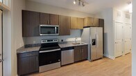 Located at 1743 Central Park Rd in Charleston, SC, this single-floor unit offers a thoughtfully designed layout with contemporary finishes throughout. The kitchen is a standout feature, equipped with stainless steel appliances including a range, over-the-range microwave, dishwasher, and a French door refrigerator with an ice and water dispenser. Rich dark wood cabinetry with sleek hardware contrasts beautifully against granite countertops, while track lighting above adds functional ambiance. Light hardwood-style flooring runs throughout the main living spaces, creating a cohesive and warm aesthetic. The open living and dining area is bathed in natural light courtesy of multiple large windows with horizontal blinds, offering views of the surrounding greenery. Neutral gray walls provide a clean, versatile backdrop throughout the unit. The bedroom is a generously sized, light-filled room with the same warm flooring and ample wall space. The bathroom is well-appointed with a full-sized soaking tub and shower combination, chrome fixtures, and neutral tiling, presenting a clean and functional design. Overall, the unit delivers a modern, move-in-ready living experience in a well-situated Charleston location.