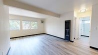 Located at 625 N State St in Ukiah, CA, this two-bedroom, one-bathroom unit offers a thoughtfully laid-out single-floor plan with consistent light wood-look flooring throughout. The open living area is bright and airy, featuring a wall-mounted A/C unit and a large window that brings in natural light and views of the surrounding neighborhood greenery. The space transitions smoothly into a combined dining and kitchen area, where warm wood cabinetry, a tile subway backsplash, butcher block countertops, and stainless steel appliances create a functional and inviting cooking space. A large picture window in the dining area frames lush outdoor tree views, filling the space with abundant natural light. The primary bedroom is generously sized, offering a wall A/C unit, large windows with neighborhood views, and a spacious walk-in closet with dual hanging rods. The second bedroom is well-proportioned with clean walls and good natural light. The bathroom features a dark wood vanity with a barn-style door, a tub/shower combo with built-in shelving, and a window above for natural ventilation. Clean lines, neutral tones, and dark baseboards give the unit a cohesive, modern-casual aesthetic throughout.
