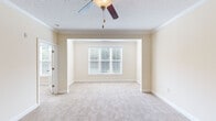 Located at 460 Seasons Place in Concord, NC, this single-floor, 2-bedroom, 1-bathroom home offers a thoughtfully designed layout with classic finishes throughout. The living area features soft carpet, crown molding, and a ceiling fan with light kit, creating a comfortable and cohesive atmosphere. Adjacent to the living space, the dining room is finished with tile flooring, chair rail molding, and an elegant chandelier, providing a polished space for everyday dining. The galley-style kitchen is outfitted with rich wood cabinetry, granite countertops, black appliances including a stove and microwave, and tile flooring — offering both functionality and style. The generously sized primary bedroom is a standout feature, boasting a large bay window that invites natural light, plush carpet, crown molding, and a ceiling fan. It also connects to a dedicated walk-in closet with wire shelving on multiple levels for ample storage. The second bedroom is bright and carpeted with windows on two walls. The bathroom includes a full tub-shower combination with brushed bronze fixtures and tile flooring. Warm neutral tones and consistent trim details unify the space throughout.