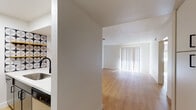This single-floor residence is designed with a clean, modern aesthetic throughout, showcasing warm light wood-tone flooring that runs consistently across all living areas. The open-concept living and dining area is bright and airy, benefiting from large sliding glass doors fitted with vertical blinds that invite generous natural light and provide access to the outdoors. A ceiling fan with an integrated light fixture adds both function and comfort to this central gathering space.

The galley-style kitchen is efficiently laid out with stainless steel appliances, including a range, microwave, and refrigerator. Dark cabinetry paired with white countertops creates a striking contrast, while a decorative patterned tile accent wall and open shelving add a contemporary design touch. A deep single-basin sink with a matte black faucet completes the space.

The two bedrooms are well-appointed, each featuring ceiling fans with light fixtures, natural light from exterior windows with blinds, and mirrored sliding closet doors that enhance the sense of space and provide ample storage.

The bathroom is thoughtfully divided, offering a separate vanity area with a wide countertop, undermount sink, dark cabinetry, and a large mirror, leading into a private water closet with a bathtub and shower combination. The consistent light flooring and crisp white walls throughout the unit create a cohesive, bright, and inviting atmosphere.