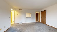 Located at 2301 Columbus Ln in Madison, WI, this single-floor unit offers a practical and functional layout with well-defined living spaces throughout. The open living area is finished with wall-to-wall carpet and features a pass-through window connecting to the kitchen, along with a sliding glass door that opens to a private balcony with outdoor views — an inviting feature that brings natural light into the space.

The kitchen is equipped with warm oak cabinetry offering ample storage, light-toned countertops, and white appliances including a range, dishwasher, and refrigerator. Light vinyl flooring completes the kitchen's clean, practical aesthetic.

The bedrooms are carpeted and generously sized. One bedroom features a ceiling fan and a window framing views of mature greenery, while another offers a structural soffit detail that adds architectural character.

Two bathrooms serve the unit. The full bathroom includes a wood-toned vanity with storage drawers, light tile flooring, and a tub-shower combination with grab bar accessibility features. A second bathroom provides a dedicated walk-in shower, also equipped with grab bars for added accessibility and safety.

Throughout the unit, warm wood-toned doors and trim provide consistent design continuity, while the neutral color palette and carpeted floors create a comfortable, move-in-ready environment.