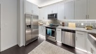 Located in Lone Tree, Colorado, this single-floor residence offers a thoughtfully designed layout that balances comfort and modern style. The kitchen is a standout feature, showcasing white shaker cabinetry, granite countertops, a gray subway tile backsplash, and a full suite of stainless steel appliances including a French door refrigerator, electric range, built-in microwave, and dishwasher. Dark hardwood-style flooring runs through the kitchen and common areas, providing a sleek, cohesive foundation.

The living area is bright and inviting, featuring large windows dressed with floor-to-ceiling drapes that allow ample natural light to fill the space. A secondary sitting or den area carries a rich blue accent wall and additional window views, adding depth and character to the home.

Both bedrooms are carpeted for warmth and comfort, each outfitted with a ceiling fan, generous windows, and closet storage. The primary bedroom offers a spacious, serene retreat, while the second bedroom is well-proportioned and versatile.

The bathroom is cleanly finished with white walls, dark hardwood-style flooring, a shower with curtain enclosure, and contemporary round woven-frame mirrors as decorative accents. Additional storage is provided through closet spaces with wire shelving throughout the home.