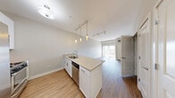 Located at 254 N York St in Elmhurst, IL, this one-bedroom, one-bathroom residence offers a thoughtfully designed open-concept layout with modern finishes throughout. The combined kitchen and living area serves as the heart of the home, anchored by a sleek peninsula with light granite-style countertops, white cabinetry, and a suite of stainless steel appliances including a refrigerator, range, microwave, and dishwasher. Pendant lighting above the peninsula and track lighting overhead illuminate the space efficiently. Warm wood-style flooring extends throughout the main living areas, complementing the neutral gray tones on the walls. The living room benefits from a large sliding glass door that invites natural light and provides access to an outdoor balcony with views of the surrounding neighborhood. The bedroom is a comfortable, well-proportioned room featuring a large window with natural light and views of the outdoors, along with a dedicated closet for storage. The bathroom is finished with large-format tile flooring, a tiled tub-shower combination with a decorative mosaic accent border, a white vanity with granite-style countertops, and brushed nickel hardware. A stacked washer and dryer unit is also included within the unit for added convenience.
