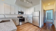 Located at 8303 Brandt Pike in Huber Heights, Ohio, this two-story residence offers a well-designed layout with contemporary finishes throughout. The kitchen is a standout feature, equipped with stainless steel appliances including a range, over-the-range microwave, and refrigerator. White shaker-style cabinetry with matte black hardware reaches toward the ceiling, complemented by granite countertops and warm wood-look flooring, creating a clean, modern aesthetic. Track lighting illuminates the space effectively.

The bedrooms are carpeted for comfort, with natural light provided by windows fitted with blinds. One upper-level room features a vaulted ceiling, adding architectural character and a sense of spaciousness. A generous walk-in closet with wire shelving and hanging rods offers ample storage.

The bathrooms carry consistent finishes, including granite-topped vanities with undermount sinks, gray shaker cabinetry, and wood-look flooring. One bathroom features a tub-shower combination, while another includes a glass-enclosed walk-in shower. A third bathroom presents a vanity with a large mirror. The overall ambiance is fresh, neutral, and move-in ready.