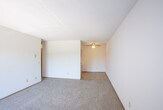 This single-floor unit offers a functional and comfortable layout designed to maximize everyday living. The living room is generously proportioned, featuring plush carpeting, a wall-mounted air conditioning unit, and a sliding glass door with vertical blinds that allow natural light to filter in. The open sightline from the living area toward the kitchen creates a connected, airy feel throughout the main living space.

The galley-style kitchen is well-equipped with warm wood-toned cabinetry lining both sides, light countertops, a double sink, a black electric range, and a refrigerator. Tile flooring runs through the kitchen, and a dedicated pantry closet adds useful storage. A ceiling fan with a light fixture overhead keeps the space bright and comfortable.

Two carpeted bedrooms offer quiet retreats, each featuring ceiling fans, baseboard heating, and windows with blinds that frame views of surrounding greenery. The bedrooms provide ample space and a calm, neutral atmosphere suited for rest and relaxation.

The full bathroom is cleanly appointed with tile flooring, a single vanity with a large mirror, and a shower-tub combination with chrome fixtures and towel bars. Throughout the unit, textured ceilings, wood-trimmed doorways, and warm neutral wall tones contribute to a cohesive and understated aesthetic.