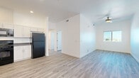 Located at 5055 N 19th Ave in Phoenix, AZ, this single-story home offers five bedrooms and two bathrooms within a thoughtfully designed layout. The interior features light wood-style luxury vinyl flooring throughout, crisp white walls, and clean architectural lines that create a bright, modern atmosphere. The open kitchen and living area serves as the heart of the home, equipped with white shaker-style cabinetry, gray countertops, a full suite of black appliances including a gas range, over-the-range microwave, refrigerator, and dishwasher, plus a dedicated pantry for additional storage. Ceiling fans are present in the living area and primary bedroom, enhancing comfort year-round. The five bedrooms are well-proportioned, each finished with the same light flooring and white walls. Several bedrooms feature windows with elevated views of the surrounding Phoenix cityscape and nearby mountain silhouettes, filling the rooms with natural light. The primary bedroom offers a generous footprint with its own ceiling fan. The two bathrooms are finished with white cabinetry, wood-tone countertops, and include a shower-tub combination. A hallway and closet complete the functional floor plan, making this home a clean, move-in-ready option in central Phoenix.