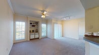 This single-floor residence offers a thoughtfully designed layout with a comfortable, cohesive flow throughout. The living room is a standout space, featuring warm neutral tones, plush carpeting, crown molding, and a ceiling fan with integrated lighting. A built-in shelving unit with cabinet storage below adds both function and character, while multiple windows and a sliding glass door with vertical blinds invite abundant natural light and provide access to an outdoor balcony with exterior views. Track lighting along the ceiling adds an additional layer of versatility to the room.

The kitchen is efficiently arranged with ample white cabinetry, dark laminate countertops, wood-style flooring, and white appliances including an electric range and an over-the-range microwave, providing everything needed for everyday cooking.

The bedrooms are generously proportioned, carpeted, and filled with natural light from large windows overlooking the outdoors. Each offers a peaceful and airy atmosphere.

The primary bathroom features wood-style flooring, a walk-in glass shower, a single-sink vanity with under-sink storage, and a well-lit mirror. The secondary bathroom includes a tiled tub-shower combination and matching wood-style flooring. A tiled hallway connects key areas of the home, adding a clean, transitional element to the overall design.