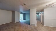 This single-floor residence offers a well-organized layout with comfortable living spaces throughout. The main living area is generously sized, featuring plush carpet flooring, textured ceilings, and a classic fireplace with a white mantle that serves as a focal point. Large sliding glass doors lead to a private balcony, allowing natural light to fill the space and providing outdoor views of surrounding greenery. A second living or dining area connects seamlessly, adding versatility to the open floor plan.

The kitchen is equipped with dark cabinetry, granite-style countertops, a tile backsplash, black appliances including an electric range and built-in microwave, and warm hardwood flooring. A pass-through opening connects the kitchen to the adjacent living space, enhancing the sense of openness.

The bedrooms are carpeted and well-proportioned, each featuring windows with blinds that bring in natural light and closet access. The bathrooms are finished with granite-style vanity countertops, white cabinetry, large mirrors, and hardwood flooring, offering a clean and functional design. Throughout the residence, a neutral color palette with cool-toned accent walls creates a calm and cohesive ambiance.