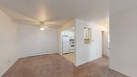 This single-floor, 2-bedroom, 1-bathroom unit offers a practical and efficiently arranged layout. The combined living room and kitchen area forms the heart of the space, where a ceiling fan overhead and baseboard heating provide year-round comfort. The living area features neutral-toned carpet and white walls, creating a clean, move-in-ready aesthetic. A front entry door opens directly into this open space, which connects seamlessly to the kitchen via a pass-through window opening. The kitchen is equipped with white cabinetry, a coil electric range with an over-the-range microwave, a full-size refrigerator, and ample counter space with a neutral laminate surface and tile flooring.

Both bedrooms are carpeted and finished in neutral tones, each supported by baseboard heating. The primary bedroom receives natural light through a large window fitted with vertical blinds. A dedicated closet features built-in shelving and double doors for organized storage. The second bedroom is comparably sized and similarly finished.

The bathroom is bright and clean, featuring tile flooring, a full-size soaking tub with a tiled shower surround, a toilet, and a vanity with counter space. A window with vertical blinds allows natural light into the room.