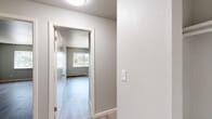Located at 155 S Academy Blvd in Colorado Springs, CO, this two-bedroom, one-bathroom residence offers a well-organized single-floor layout with a clean, neutral aesthetic throughout. Light-toned wood-look flooring runs through the main living areas, complementing the soft gray walls and white trim that give the space a bright, modern feel.

The living room is an open, airy area anchored by a sliding glass door that floods the room with natural light and provides direct access to a private balcony. The balcony overlooks a canopy of mature trees, offering a peaceful outdoor retreat. A wall-mounted air conditioning unit and baseboard heating ensure year-round comfort.

The spacious primary bedroom features a wide window with views of the surrounding greenery, baseboard heating, and durable wood-look flooring. The second bedroom is similarly appointed and includes a built-in closet with a rod for ample storage. A connecting hallway links the bedrooms and living spaces efficiently.

The bathroom is a standout feature, showcasing a full tub and shower combination surrounded by striking marble-patterned wall panels in white and gray tones, paired with neutral tile flooring. The overall design of the space is practical yet polished, making it a comfortable and functional home in Colorado Springs.