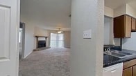Located at 3555 Cedar Creek Dr in Shreveport, Louisiana, this single-story, 2-bedroom, 1-bathroom home offers a functional and comfortable layout. The spacious living room serves as the heart of the home, featuring plush carpeting, a ceiling fan, and a standout wood-burning fireplace framed by a rustic wood mantel and brick hearth. A sliding glass door with vertical blinds fills the room with natural light and provides outdoor access. The kitchen is designed in a galley style with wood cabinetry, dark granite-style countertops, a double sink, and white appliances including a range and refrigerator. A pass-through counter with a dark countertop edge connects the kitchen to the living area, adding a convenient serving or casual dining option. The two bedrooms are carpeted and equipped with ceiling fans, offering comfortable retreats. The primary bedroom features its own walk-in closet with dual shelving rods on each wall, providing generous storage. The full bathroom includes a vanity with dark countertops, wood cabinetry, a large mirror, a bathtub, and durable hardwood-style flooring. A connecting hallway links the bedrooms and bathroom efficiently. The overall aesthetic is warm and practical, with neutral tones throughout.