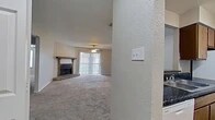 Located at 3555 Cedar Creek Dr in Shreveport, Louisiana, this single-story, 2-bedroom, 1-bathroom home offers a functional and comfortable layout. The spacious living room serves as the heart of the home, featuring plush carpeting, a ceiling fan, and a standout wood-burning fireplace framed by a rustic wood mantel and brick hearth. A sliding glass door with vertical blinds fills the room with natural light and provides outdoor access. The kitchen is designed in a galley style with wood cabinetry, dark granite-style countertops, a double sink, and white appliances including a range and refrigerator. A pass-through counter with a dark countertop edge connects the kitchen to the living area, adding a convenient serving or casual dining option. The two bedrooms are carpeted and equipped with ceiling fans, offering comfortable retreats. The primary bedroom features its own walk-in closet with dual shelving rods on each wall, providing generous storage. The full bathroom includes a vanity with dark countertops, wood cabinetry, a large mirror, a bathtub, and durable hardwood-style flooring. A connecting hallway links the bedrooms and bathroom efficiently. The overall aesthetic is warm and practical, with neutral tones throughout.