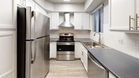 This single-floor residence offers a thoughtfully designed layout with modern finishes throughout. The kitchen is a standout feature, outfitted with stainless steel appliances including a refrigerator, electric range with a sleek overhead hood vent, and dishwasher. White shaker-style cabinetry pairs with dark countertops and a classic white subway tile backsplash, while light wood-look flooring ties the space together with a clean, contemporary aesthetic. A window with horizontal blinds brings in natural light, keeping the kitchen bright and functional. The open living area is characterized by neutral-toned walls, wood-look flooring, and a textured ceiling. Sliding glass doors lead to an outdoor space, allowing natural light to fill the room. A secondary living or flex area connects seamlessly, providing flexible use of the space. The bathroom features white cabinetry with brushed nickel hardware, a dark countertop with an inset sink, a large mirror with vanity lighting, and a glass-door shower enclosure. The bedroom is spacious with matching flooring and a textured ceiling, and includes access to a dedicated walk-in closet, offering generous storage. Overall, the space presents a cohesive, updated interior with a neutral palette ideal for a variety of lifestyles.