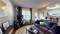 Located at 3535 E 10th St in Greenville, NC, this single-floor multi-bedroom unit offers a well-designed layout suited for shared living. The open living room serves as the heart of the space, featuring rich hardwood-style flooring, large windows dressed with teal curtains that invite natural light, and a stylish accent wall with built-in shelving and contemporary sconce lighting. A breakfast bar connects the living area to the galley-style kitchen, which is equipped with white cabinetry, granite-look countertops, a full suite of white appliances, and a window above the sink that brings in additional natural light. Multiple bedrooms provide comfortable, personalized retreats, each featuring ceiling fans, carpeted floors, and ample closet space. One bedroom showcases a bold navy accent wall, while another includes a built-in desk nook ideal for studying. Both bathrooms are well-appointed with wide vanity countertops, large mirrors, and hardwood-style flooring. The overall layout is practical and spacious, designed to comfortably accommodate multiple residents while maintaining a cohesive and inviting aesthetic throughout.