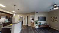This single-floor residence offers a thoughtfully designed open-concept layout that seamlessly connects the kitchen, dining, and living areas. The interior is finished with rich dark hardwood-style flooring throughout the main living spaces, complemented by warm taupe-toned walls that create a cohesive and inviting atmosphere.

The kitchen is a standout feature, outfitted with dark espresso cabinetry, granite-style countertops, and a full suite of stainless steel appliances including a refrigerator, electric range, microwave, and dishwasher. Pendant lighting above the breakfast bar adds a polished touch. An adjacent dining area provides space for casual meals, while a conveniently tucked in-unit washer and dryer closet adds practical functionality.

The living room is bright and welcoming, featuring a ceiling fan, sliding glass doors that open to a private outdoor patio, and ample wall space for a wall-mounted television. Natural light fills the room through the large patio-facing window.

The bedroom is a comfortable retreat with plush carpeting, a ceiling fan, a natural light window with curtain panels, and a walk-in closet. The bathroom features a dark wood vanity with a wide mirror, granite-style countertop, and a full tub-shower combination with hardwood-style flooring for a clean, contemporary finish.