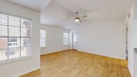 This single-story, one-bedroom, one-bathroom unit offers a thoughtfully arranged layout that maximizes its compact footprint. The living room is a standout space, featuring vaulted ceilings that create a sense of openness well beyond its physical dimensions, complemented by light hardwood-style flooring, a ceiling fan, and multiple windows fitted with blinds that allow ample natural light to filter in.

The kitchen is equipped with stainless steel appliances, including an electric range and over-the-range microwave, paired with white cabinetry and granite countertops that provide a clean, modern aesthetic. The same granite countertop and white cabinetry design continues into the bathroom, which also includes a tub-shower combination and overhead storage cabinets.

The bedroom features plush carpeting, a ceiling fan, and a sliding glass door with vertical blinds offering outdoor views and additional natural light. A dedicated closet and an in-unit laundry area with a full-size washer provide practical functionality. Throughout the unit, white walls and consistent finishes contribute to a bright, cohesive ambiance.