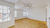 This single-story, one-bedroom, one-bathroom unit offers a thoughtfully arranged layout that maximizes its compact footprint. The living room is a standout space, featuring vaulted ceilings that create a sense of openness well beyond its physical dimensions, complemented by light hardwood-style flooring, a ceiling fan, and multiple windows fitted with blinds that allow ample natural light to filter in.

The kitchen is equipped with stainless steel appliances, including an electric range and over-the-range microwave, paired with white cabinetry and granite countertops that provide a clean, modern aesthetic. The same granite countertop and white cabinetry design continues into the bathroom, which also includes a tub-shower combination and overhead storage cabinets.

The bedroom features plush carpeting, a ceiling fan, and a sliding glass door with vertical blinds offering outdoor views and additional natural light. A dedicated closet and an in-unit laundry area with a full-size washer provide practical functionality. Throughout the unit, white walls and consistent finishes contribute to a bright, cohesive ambiance.