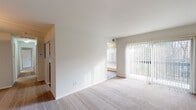 This single-floor residence offers a thoughtfully arranged layout that balances comfort and functionality throughout. The living area is generously sized, featuring plush neutral carpeting and crisp white walls that create a bright, airy atmosphere. A full-length vertical blind-covered sliding glass door floods the space with natural light and provides views of lush greenery outside, lending a tranquil, connected-to-nature feel. An open passageway leads to a secondary living or dining area, extending the sense of space seamlessly.

The galley-style kitchen is well-equipped with warm wood cabinetry, dark granite-style countertops, hardwood-style flooring, and a full suite of black appliances including a range, microwave, refrigerator, and dishwasher. Ample upper and lower cabinet storage ensures practical functionality.

The bedrooms are carpeted and feature windows with garden views, offering a peaceful retreat. Each room is finished with clean, neutral tones and ceiling-mounted light fixtures.

Two bathrooms serve the residence, each featuring hardwood-style flooring, white vanities, and framed mirrors. One includes a shower stall, while the other offers a full soaking tub with tiled surround, providing versatile options for daily routines. The overall ambiance of the space is clean, bright, and move-in ready.