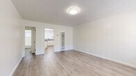 Located at 345 S Westlake Ave in the Westlake neighborhood of Los Angeles, this efficiently designed single-floor unit offers a clean, modern aesthetic across four well-defined spaces. Light wood-style plank flooring runs consistently throughout, creating a cohesive and airy feel that maximizes the sense of space.

The living room serves as the heart of the unit, featuring bright white walls, a textured ceiling, and a window that allows natural light and greenery views to fill the room. A wall-mounted AC unit ensures year-round comfort, while clean baseboards and a neutral palette keep the space feeling open and versatile.

The kitchen is thoughtfully laid out with white cabinetry, grey laminate countertops, and a full suite of stainless steel appliances including a gas range, over-range microwave, and refrigerator. A window above the sink brings in natural light, enhancing the clean, functional workspace.

The bathroom continues the bright, white theme with a full bathtub and shower combination, a toilet, and a vanity with matching grey countertop. A frosted window provides natural ventilation while maintaining privacy.

A hallway connects the spaces efficiently, contributing to the unit's smart, compact layout. Overall, the space presents a fresh, move-in-ready environment with consistent finishes and practical amenities throughout.
