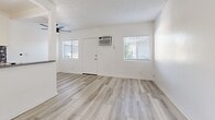 Located at 5119 Fountain Ave in the heart of Los Angeles, this one-bedroom, one-bathroom unit offers a thoughtfully designed single-floor layout that maximizes every square foot. Light wood-style flooring runs throughout, creating a cohesive and clean aesthetic across all rooms.

The combined kitchen and living area serves as the heart of the unit. The kitchen features white shaker-style cabinetry with black hardware, grey stone-look countertops, a stainless steel gas range, and a striking black-and-white patterned tile backsplash that adds a bold design accent. Track lighting overhead and a peninsula-style counter provide both function and style. The adjacent living area is bright and open, with multiple windows fitted with blinds, a wall-mounted A/C unit, and a ceiling fan.

The bedroom is a comfortable, well-proportioned space featuring a sliding glass door that opens to an outdoor view, filling the room with natural light. A mirrored sliding closet door adds depth to the space.

The bathroom is finished with a white subway tile tub/shower surround, a stone-look countertop vanity with white cabinetry, black-framed mirrors, and chrome fixtures, delivering a clean, modern aesthetic throughout.